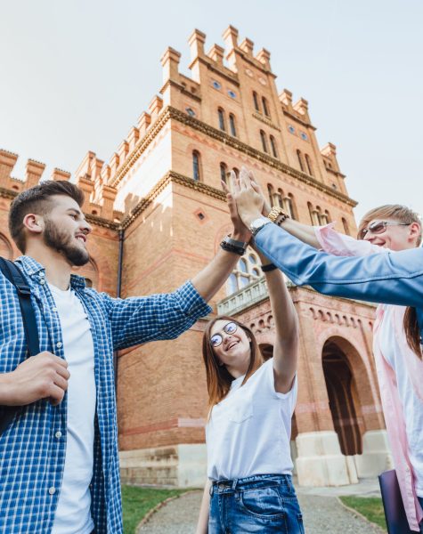 Low angle of cheerful team of students passed the test by preparing all together. Success, fun, friendship, education concept. Four graduates are celebrating outside. Casual clothes.